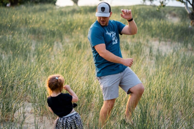 man dancing in a field with his daughter